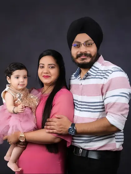 A lovely family portrait with a father in a turban, a mother in a pink dress, and their baby girl. A picture of a happy and proud family.