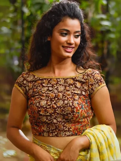 This boat-neck blouse features a classic brown Kalamkari print. The cap sleeves and simple cut make it a versatile piece for both casual and semi-formal occasions.