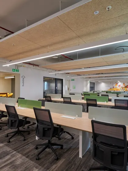 An open workspace with long benching-style desks to promote collaboration. The use of wood-fiber acoustic panels on the ceiling helps to control noise in the open environment.