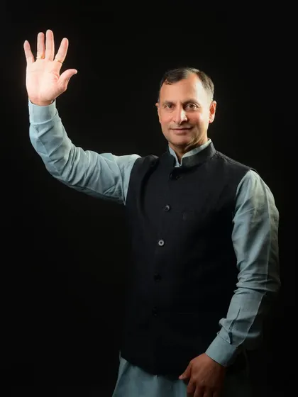 A politician's portrait with a wave, a classic pose for campaign materials. It's designed to be open, friendly, and engaging for the public.