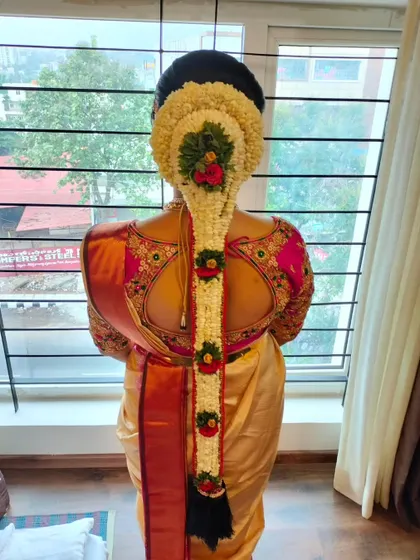 A full length view of a traditional floral 'Jadai', showing how the hairstyle complements the bride's posture and saree.