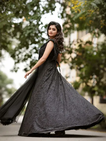 The dramatic flair of this black evening gown makes it a perfect choice for an outdoor shoot with a touch of mystery and elegance.
