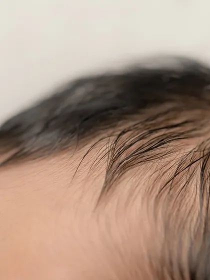 A close-up of the soft, fine hair on a newborn's head. These are the fleeting details that change so quickly.