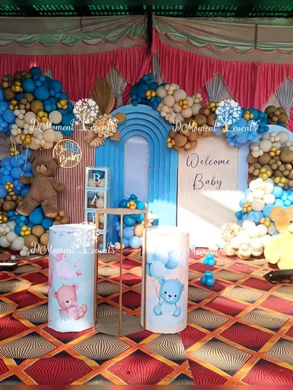 A charming teddy bear themed setup for a baby welcome party, featuring a blue and brown color scheme, themed pedestals, and a large teddy bear prop.