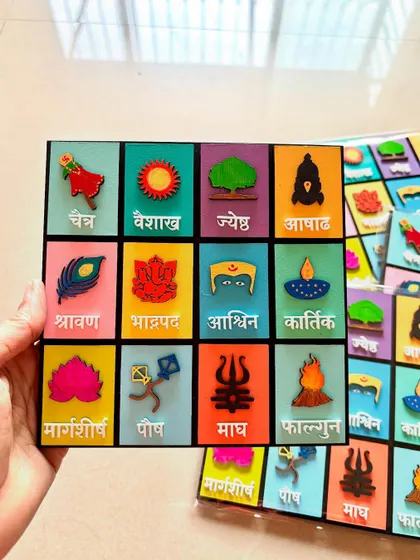 Holding my handcrafted Marathi calendar. Each square represents a month with its corresponding festival or symbol, adding a touch of Marathi elegance to your home.