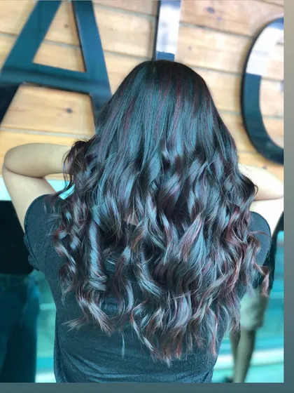 A full view of the violet highlights on wavy hair. This is a great option for someone wanting a touch of unconventional colour.