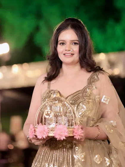 Golden glam for a party. This client is holding a decorative birdcage, looking absolutely charming in her sequined lehenga.