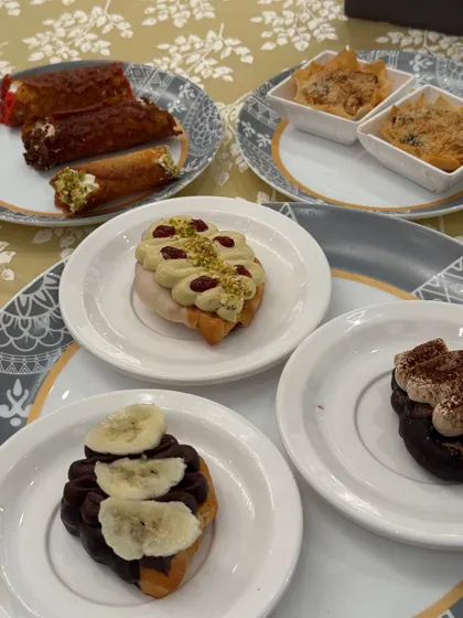 A beautiful assortment of our desserts on a guest's plate, including cannolis, filo tarts, and topped croissants. Proof that food is the real main character.