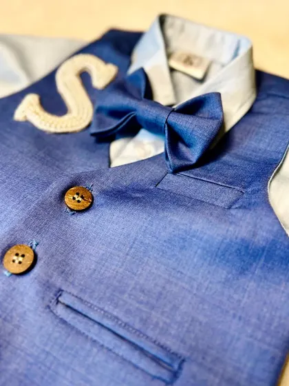 A close-up on the details of our boys' navy suit, showing the texture of the fabric and the beautifully crafted embroidered initial.
