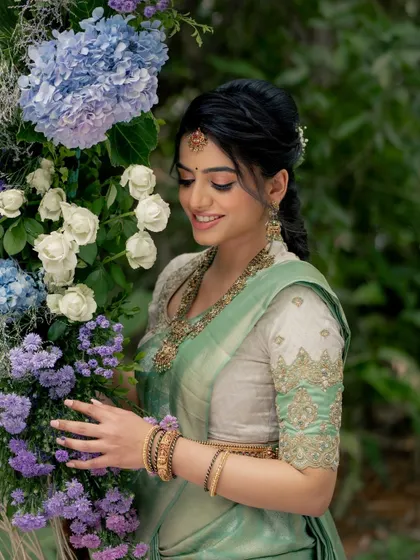 A beautiful shot of the bride interacting with the floral decor. The makeup is soft and pretty, perfect for this gentle, romantic setting.