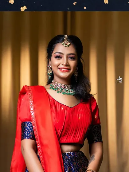 A smiling client in a modern red and blue lehenga, perfect for a sangeet or party.