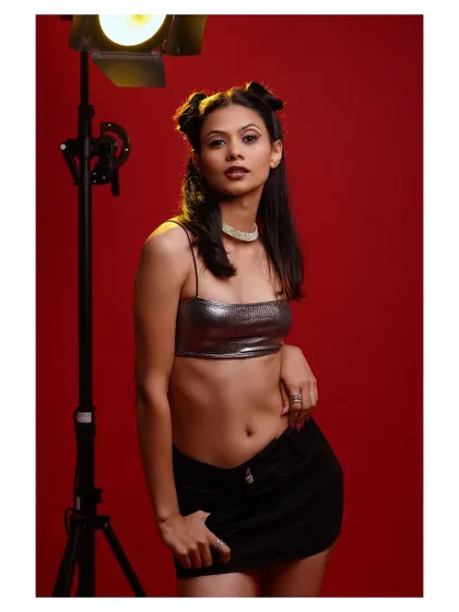 A dynamic studio shot with dramatic lighting. The model's pose and the red background create a high-energy, eye-catching fashion photograph.