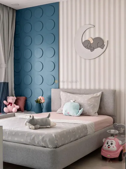 This calming kid's bedroom uses a soft grey and blue color palette. The wall features a cute sleeping elephant on a moon decal and a textured 3D circle panel.