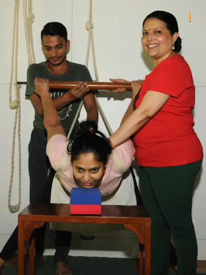 Look at the focus and smiles. Here, I am assisting a student in a supported backbend, using a stool, blocks, and ropes. This setup allows for a deep opening of the chest and spine, which is incredibly therapeutic and emotionally releasing.