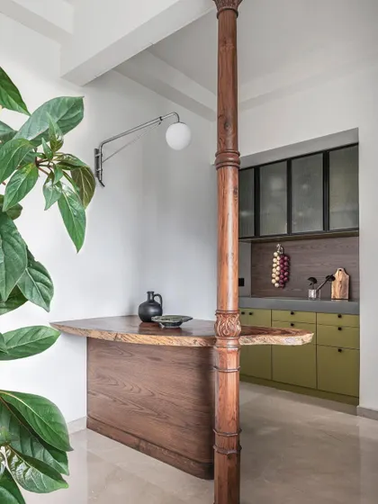 The open-plan kitchen and bar area in Apartment 1501. A reclaimed wooden column and a live-edge bar top add character and a playful touch to this modern, functional space.