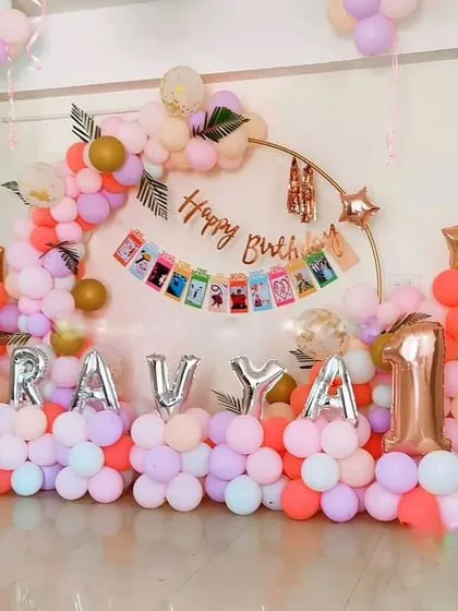 A lovely pastel-themed first birthday. This setup includes a circular frame with a "Happy Birthday" banner, balloon letters for the name, and a number '1' foil balloon.