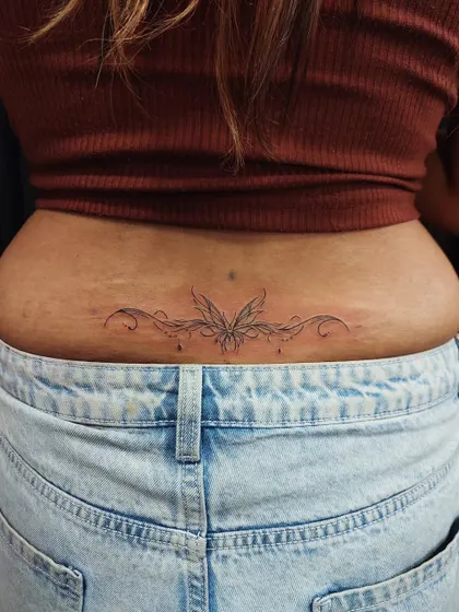 A delicate ornamental design for the lower back. This symmetrical, fine-line tattoo is an elegant and sensual piece of body art.