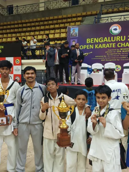 A candid photo with my students after a successful day at the Bengaluru Open Karate Championship, celebrating their hard-earned trophies and medals together.