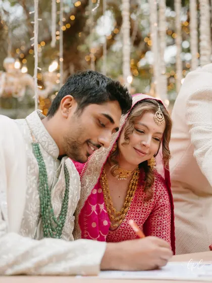 A candid moment of the couple signing their marriage certificate. The makeup is flawless yet understated, perfect for these intimate, up-close moments.