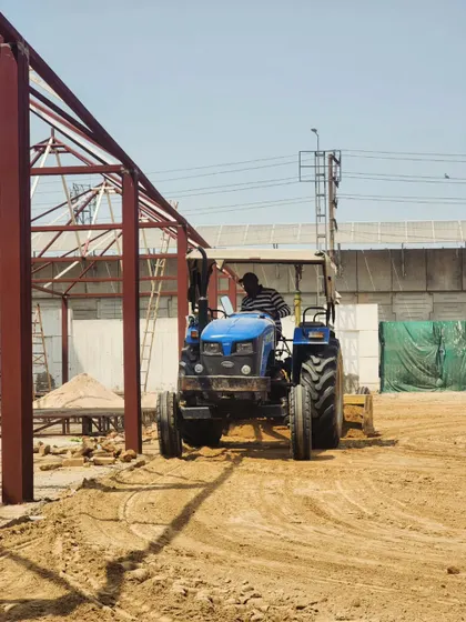 Our operator carefully maneuvers the tractor around new construction, demonstrating our ability to work on complex and active project sites.