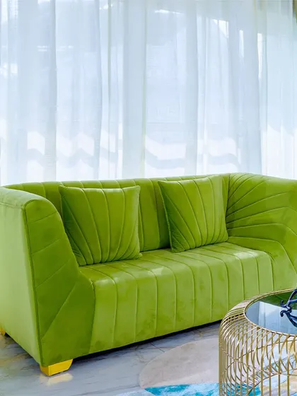 A close-up of the stylish green sofa, showing the detailed pleating and comfortable design.