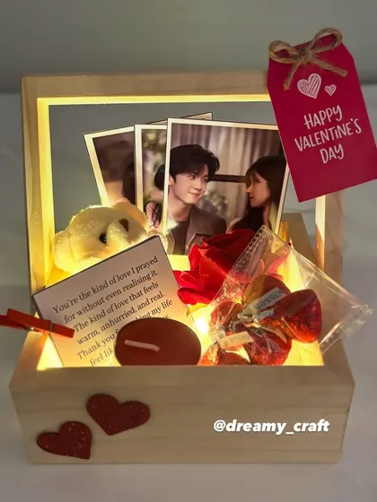 This lit-up Valentine's hamper creates a warm and romantic glow. It's a small wooden basket filled with photos, a teddy, a love note, and other sweet treats.