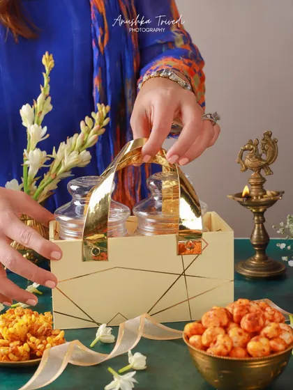 A lifestyle shot showing a premium Diwali hamper with glass jars being held, emphasizing the human element of gifting.