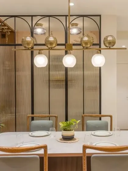 A luxurious dining area with a marble-top table, set against a fluted glass partition with an arched design.