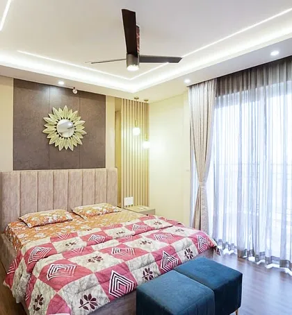 A wider view of the bedroom, showing how the floor-to-ceiling curtains allow natural light to filter in, creating a calm and grounded energy. The design is meant to be relevant for years to come.