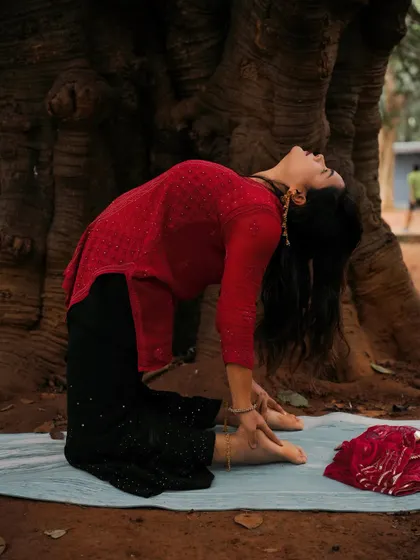 Ustrasana, or Camel Pose, practiced outdoors. This backbend opens the entire front of the body, including the chest, abdomen, and quadriceps. It's known for being an energizing and heart-opening pose.