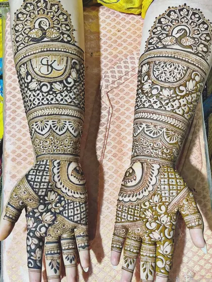 This design shows the mehndi in two stages: one side with the fresh paste and the other with the stain developing. It features a peacock and the initial "K" in a classic bridal style.