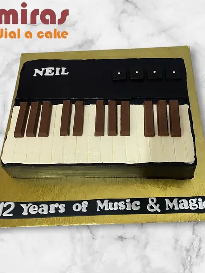 A sleek and stylish piano cake for a music lover. This fondant-free cake is shaped like a keyboard, celebrating "12 Years of Music & Magic" in a delicious way.