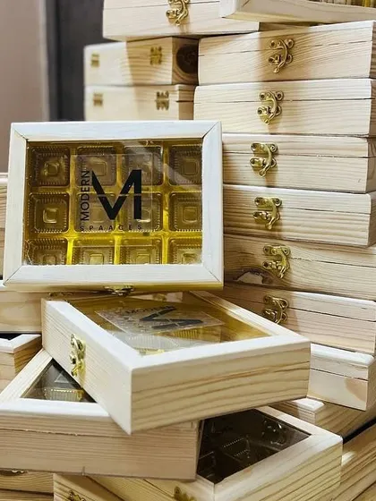 Stacks of custom wooden chocolate boxes with a clear lid showing the 'Modern Spaaces' logo. These are perfect for client thank you gifts or event favors.