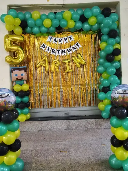 A Minecraft theme birthday decoration for a 5th birthday. The green, yellow, and black balloons match the game's aesthetic, complete with themed character and game-world balloons.
