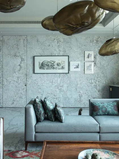 The living room is a masterpiece of artful living, featuring antique silver birds from Chor Bazaar and a celestial 'Bocci clouds' light installation. A water feature with art by Ankush Safaya adds a serene, symbolic element.