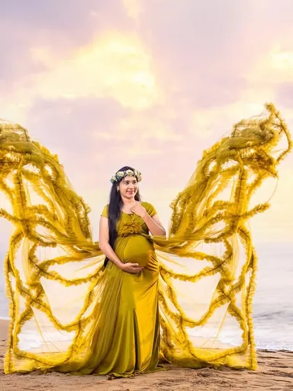 A fantasy edit of our butterfly gown, transforming the mom-to-be into a magical creature against a dreamy beach sunset.