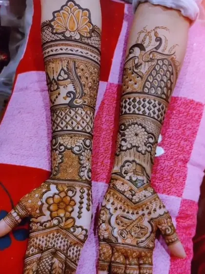 This intricate design is filled with a variety of motifs, including peacocks, elephants, and a dhol, covering the hands completely.