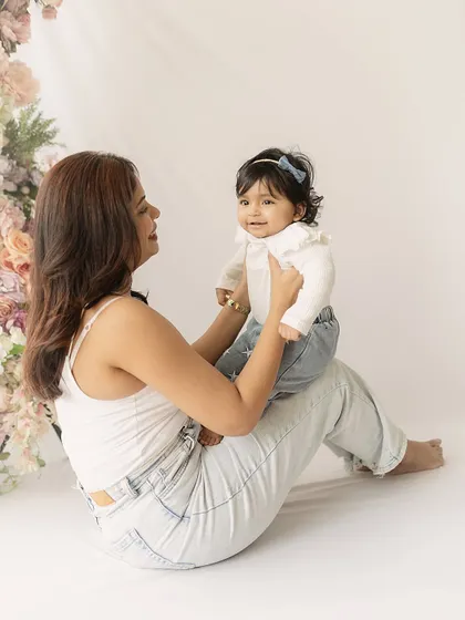 A sweet interaction between mother and daughter. The baby's happy expression and the mother's gentle hold create a heartwarming scene.