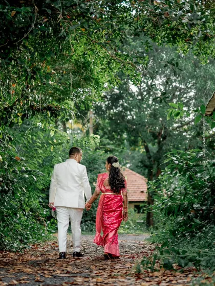 The couple walks hand-in-hand down a leaf-strewn path, a classic romantic shot from their outdoor engagement session.