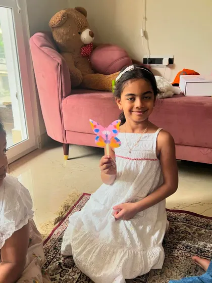 Holding up her pink and blue butterfly. Each child's creation is a unique reflection of their imagination.