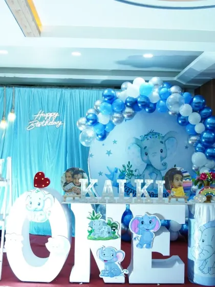 Another angle of the elephant-themed birthday decor, showing the arrangement of props and the "Happy Birthday" lighting against the blue curtain backdrop.