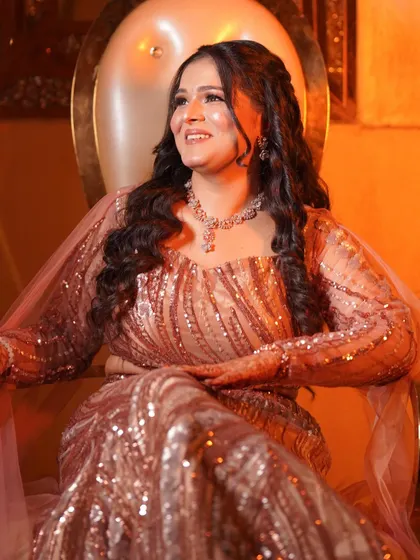 The bride seated like a queen, her sequined dress and glamorous makeup shining under the warm lights.