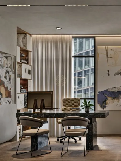 Art and texture bring personality to a leadership cabin. A bold marble desk is set against a backdrop of abstract art and custom shelving, creating a sophisticated space that reflects a modern aesthetic while remaining highly functional.