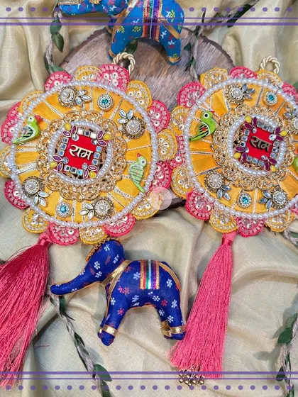 These stunning Indo-Western "Ram Ram" signs are part of a cherished ritual that strengthens the sibling bond. This yellow and pink design with parrot motifs and tassels is a beautiful blend of heritage and modern style.