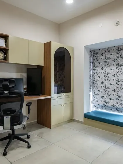 This study area is cleverly designed to include a cozy window seat with a blue cushion. The custom desk and storage unit provide a complete and comfortable workspace with plenty of natural light.
