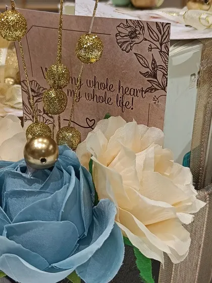 A close-up of an engagement hamper for him, featuring a 'With my whole heart' card and beautiful blue and cream floral decorations.