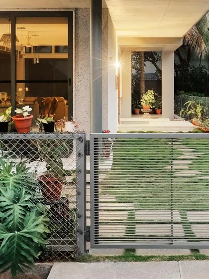 A view of the entrance at dusk, showing how the warm interior light glows through the large glass sliding doors. The design creates a welcoming and transparent feel.