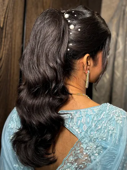 A modern and chic high ponytail with pearl accessories, perfect for a sangeet or cocktail party.
