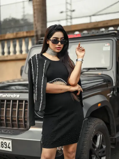 A close-up shot focusing on the model's confident expression and accessories, with the jeep in the background.