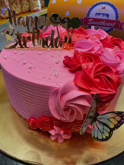 A beautiful pink birthday cake decorated with buttercream roses and a delicate butterfly. The design is romantic and elegant, perfect for a special birthday.